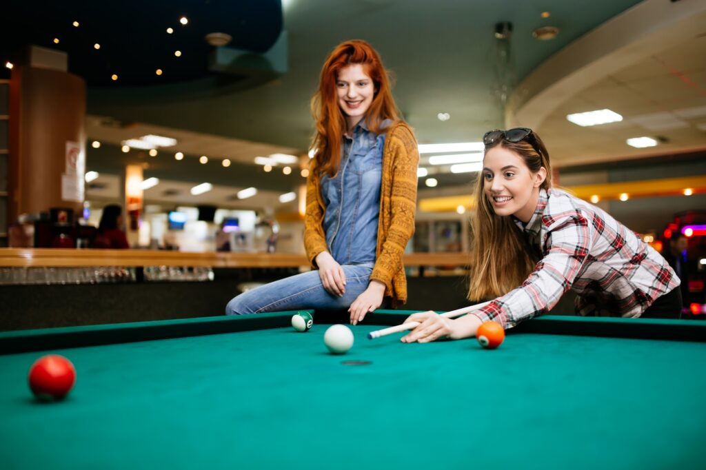 Happy young friends playing snooker and billiards